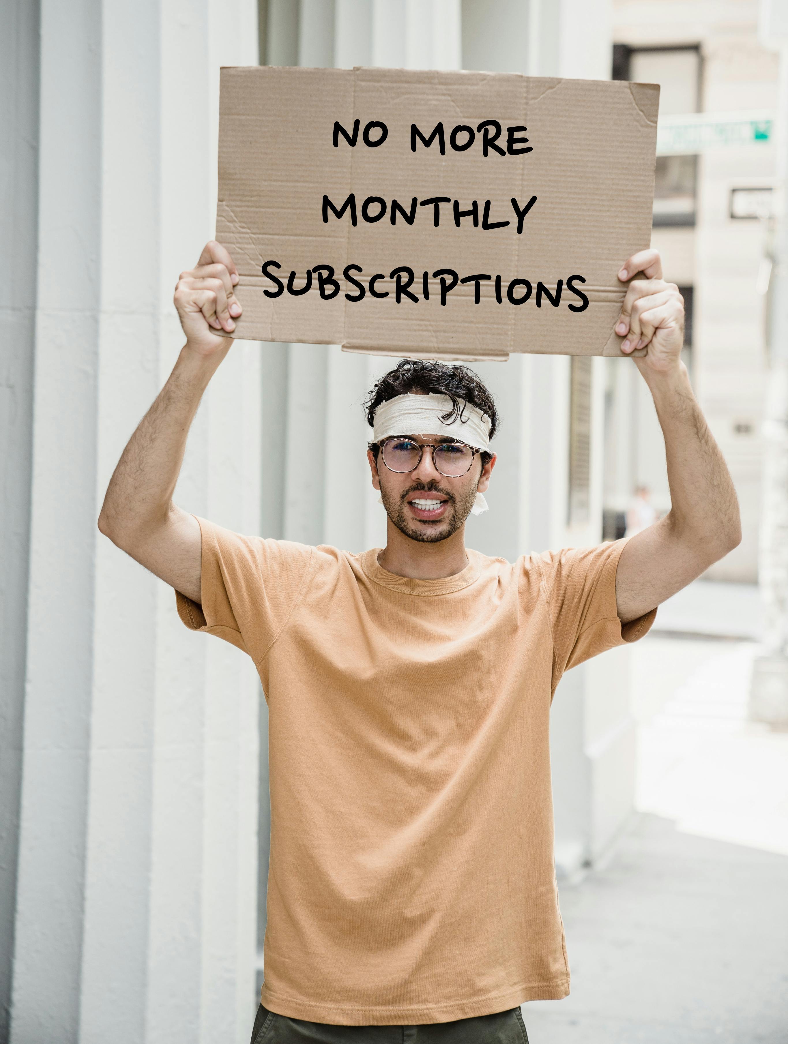 Protester holding a placard that says 'No More Monthly Subscriptions'.